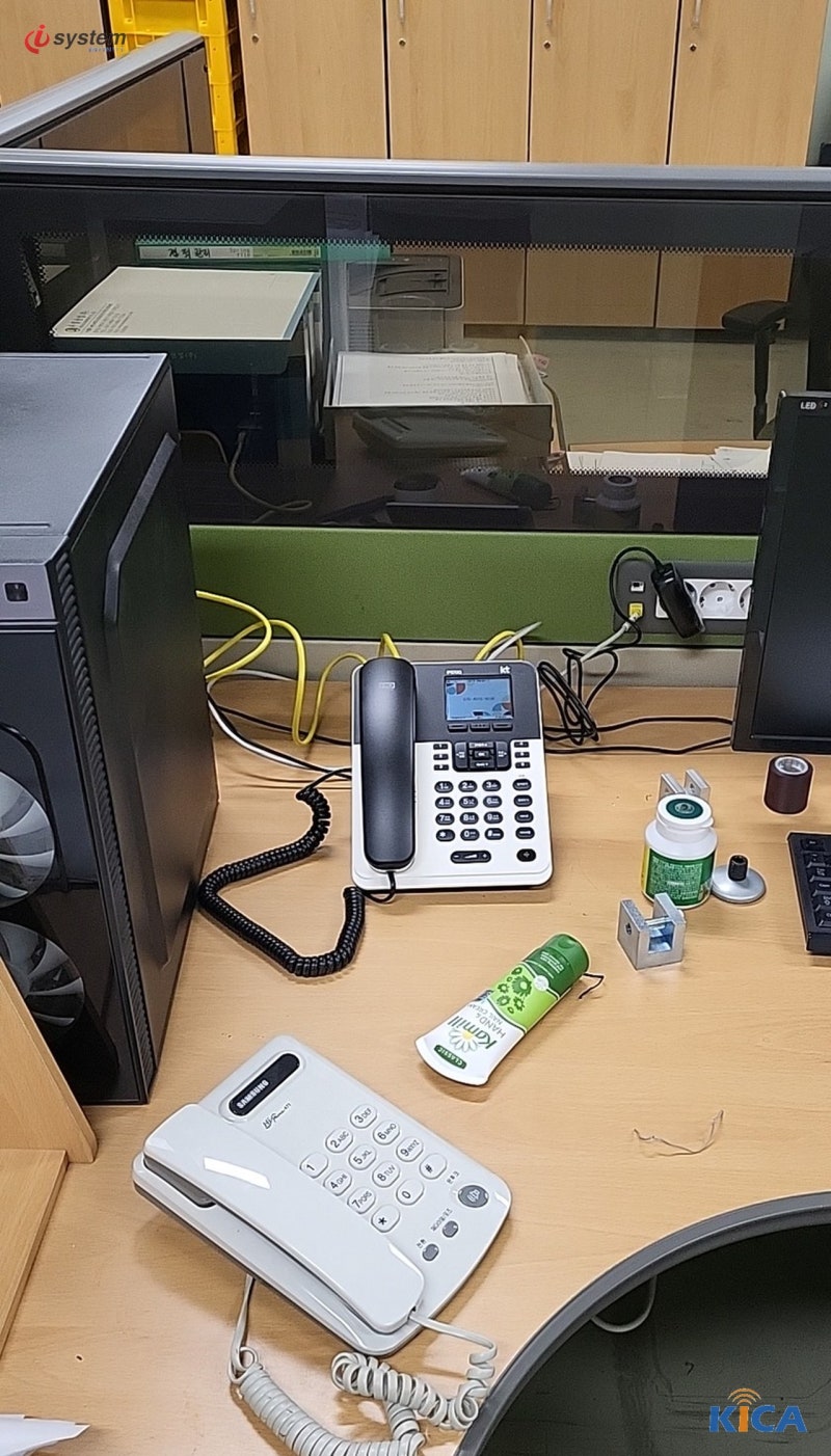 사무실 책상 위 KT 인터넷전화기와 뒤쪽으로 이어진 노란색 랜 케이블, 앞쪽의 흰색 전화기