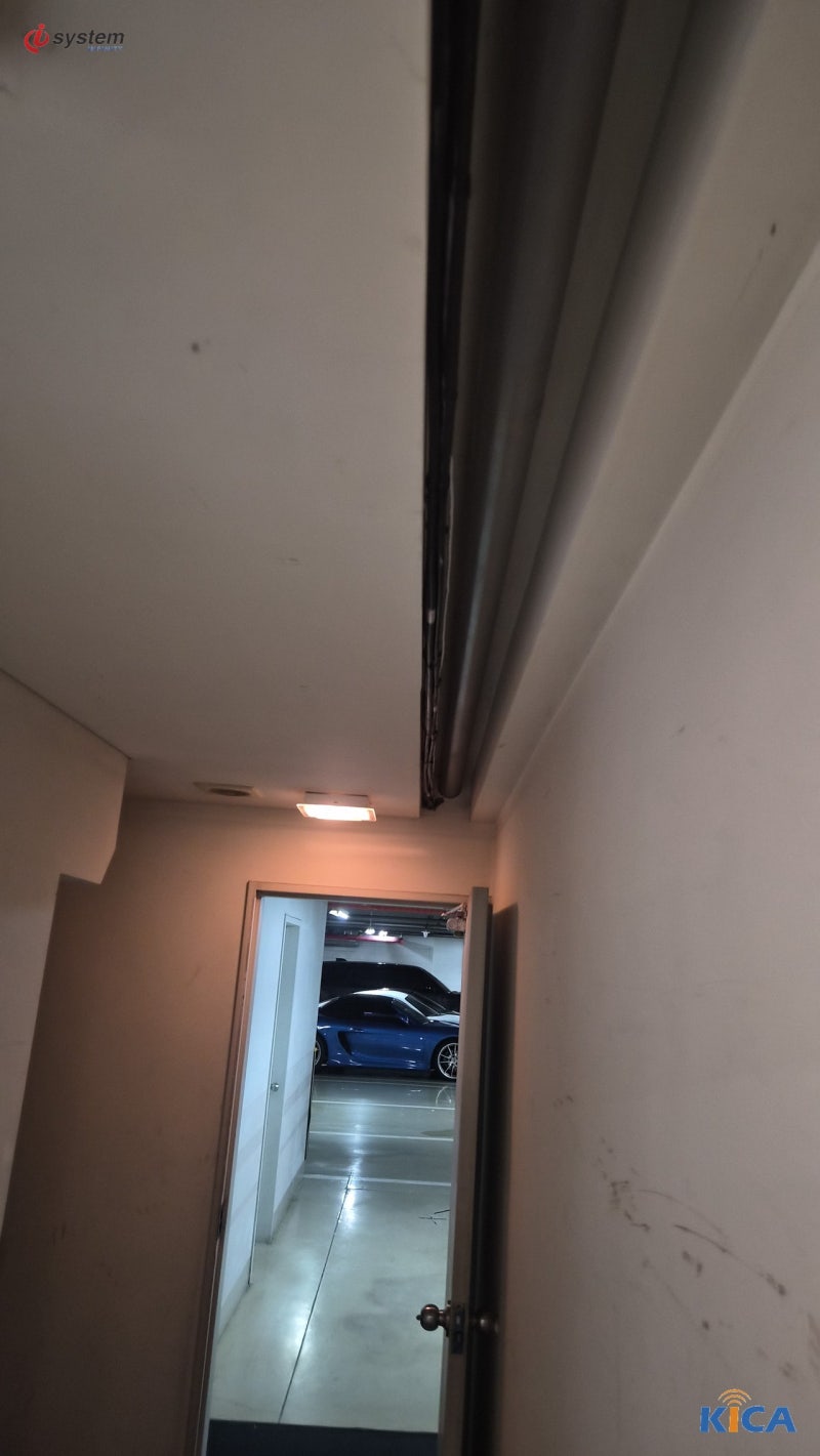 복도 천장 틈새를 따라 매립된 통신 케이블과 주차장으로 이어지는 출입문