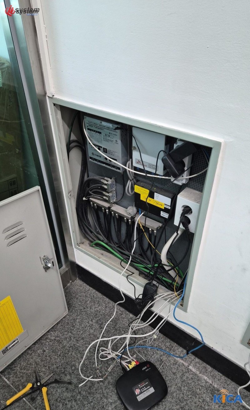 벽면에 매입된 통신 단자함 내부, 여러 가닥의 케이블과 장비가 정리되어 연결된 모습