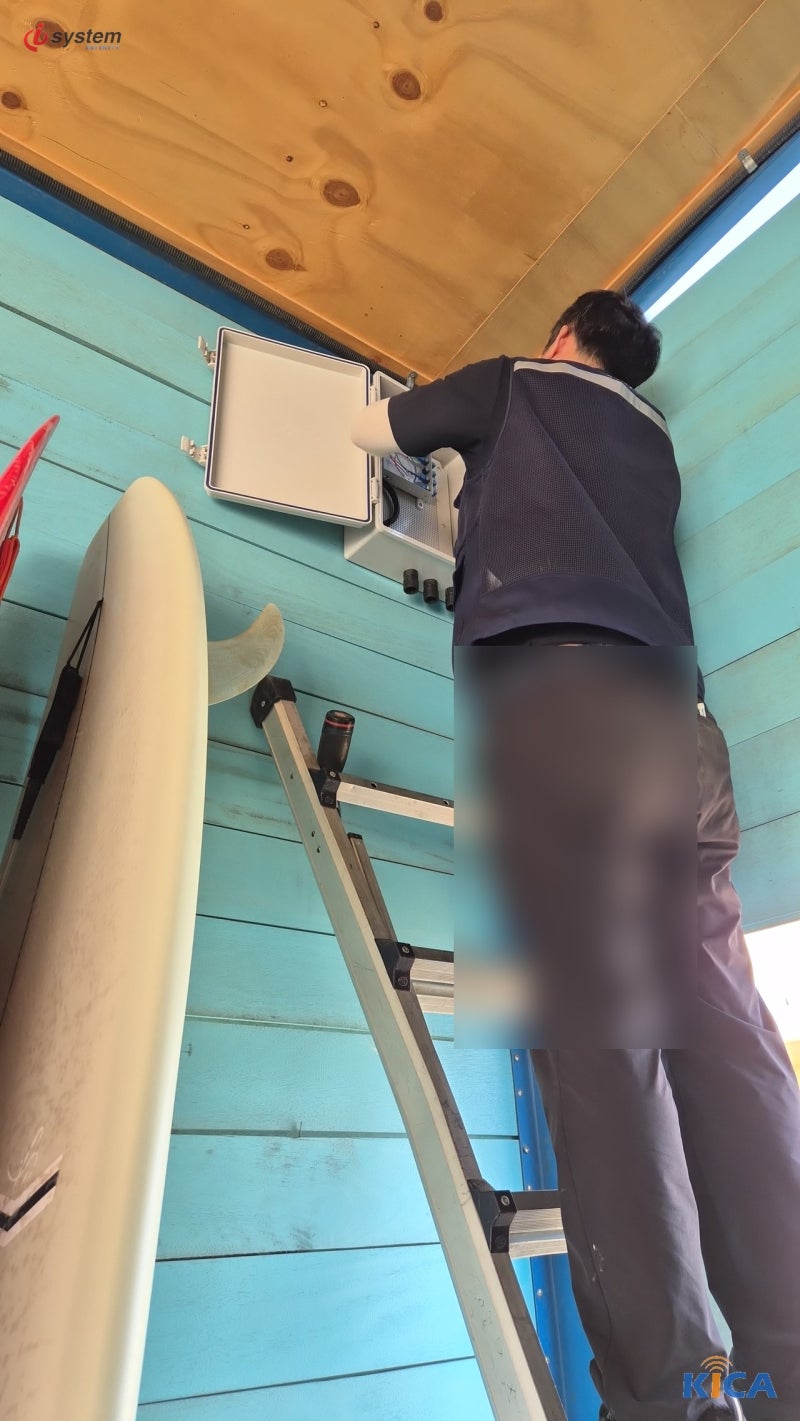 [시흥 야외 매장] 시원한 민트색 판넬로 마감된 매장 외벽 상단에 야외용 하이박스 단자함을 안착시킨 뒤 내부 결선에 들어간 모습 - 매장 네트워크 설치