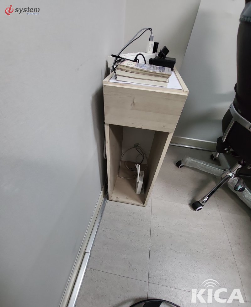 사무용 이동식 책상 박스 안에 보관된 소형 무선 라우터 — 사무 가구와 함께 정리된 통신 장비